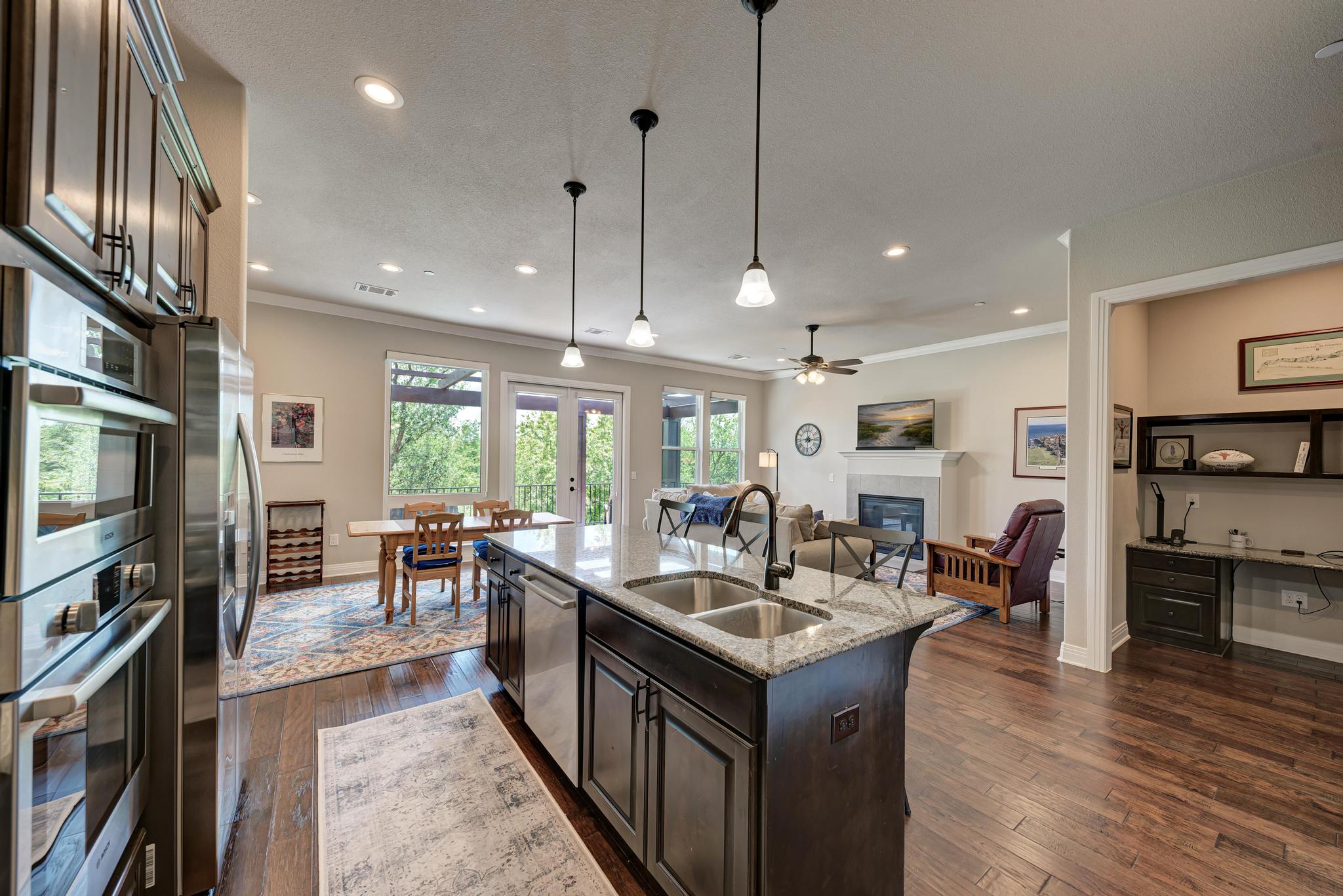 2601 North Quinlan Park Road, Unit 506 Austin, TX 78732 - Photo 16 of 39 Granite counters and stainless steel appliances complete this open-concept kitchen, flowing into a warm living area.