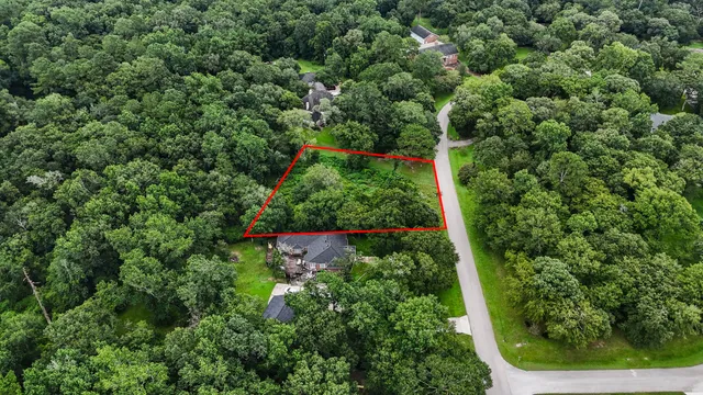 an aerial view of residential house with outdoor space and trees all around
