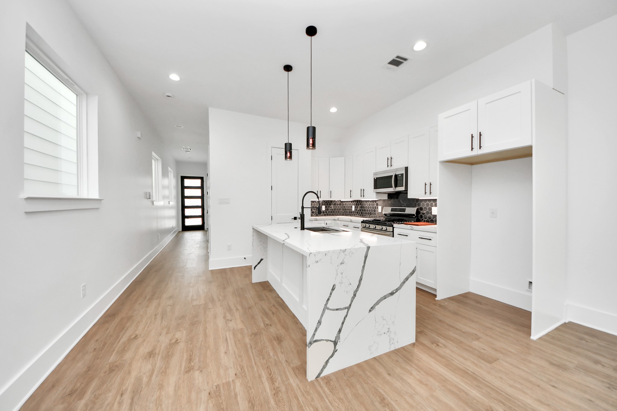 a kitchen with stainless steel appliances white cabinets a sink a stove a refrigerator and a window