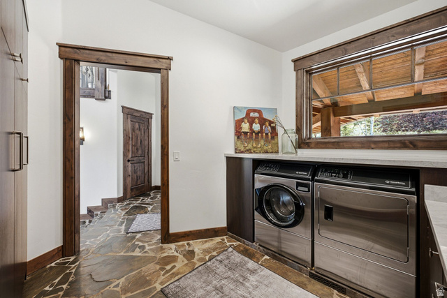 7885 North Rabbitbrush Court, Unit 13 Park City, UT 84098 - Photo 33 of 88 Laundry area featuring natural stone flooring, dark wood-finish cabinetry, light-toned countertops, and a large wood-framed window
