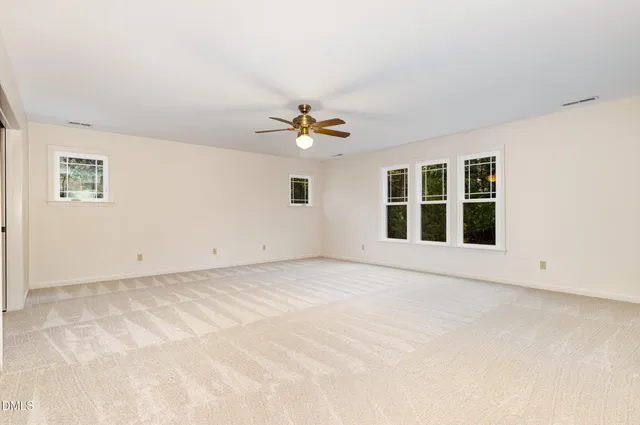 an empty room with a bathroom and a chandelier fan