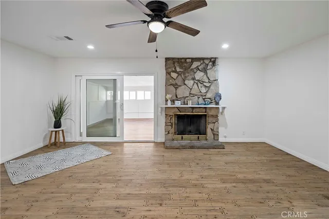 a view of an empty room with a fireplace and a chandelier fan