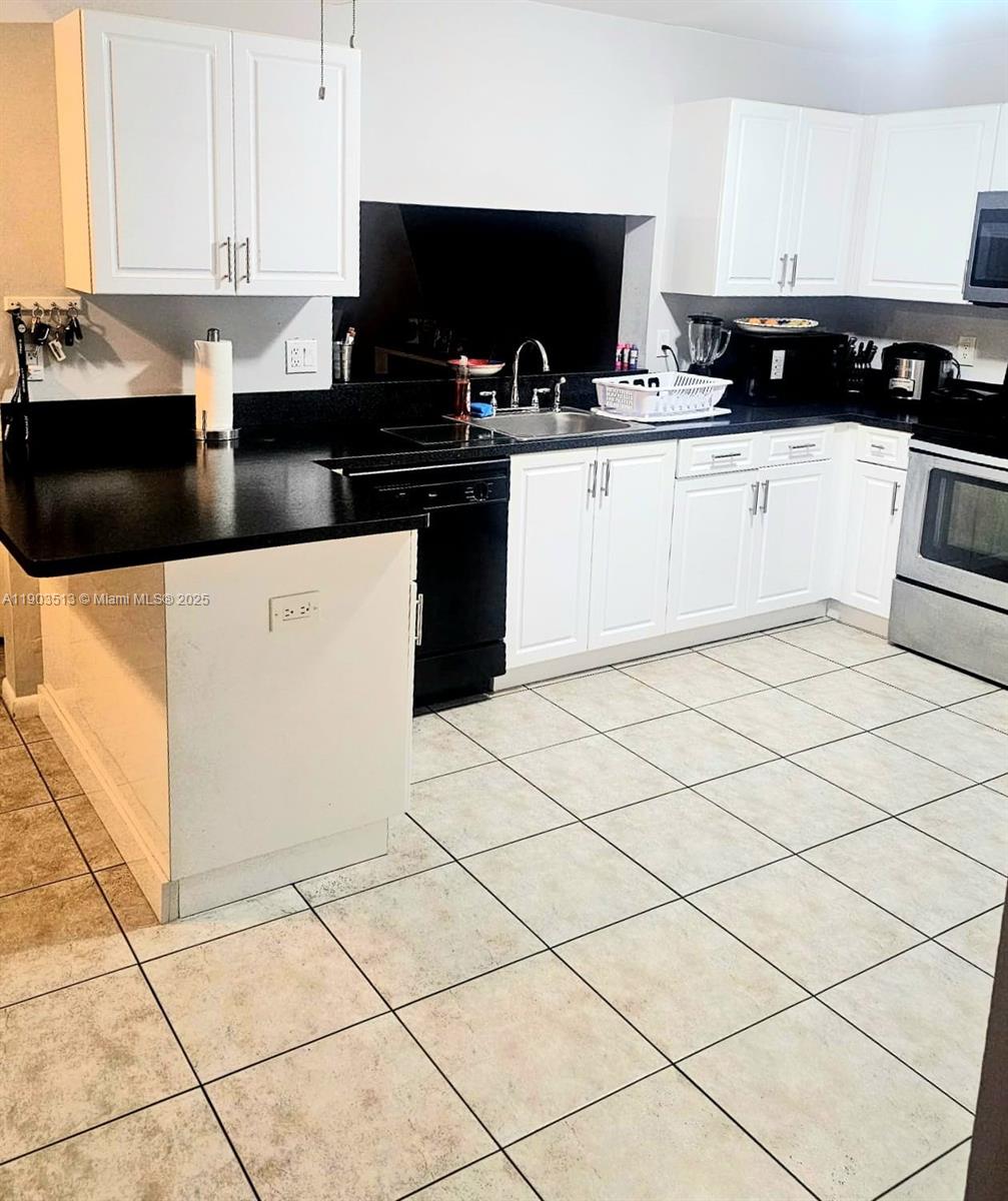 10830 Northwest 8th Street Pembroke Pines, FL 33026 - Photo 18 of 69 a kitchen with granite countertop white cabinets and black appliances