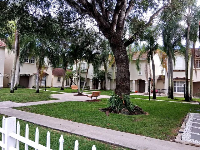a front view of a house with a yard and palm trees