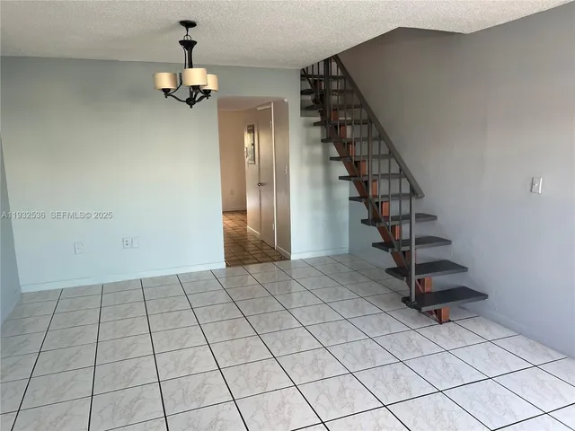 a view of an empty room with stairs and wooden floor