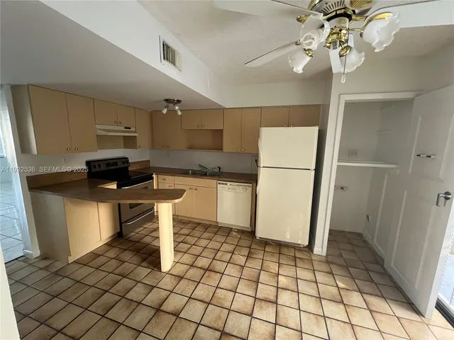 a kitchen with a refrigerator a stove top oven and cabinets