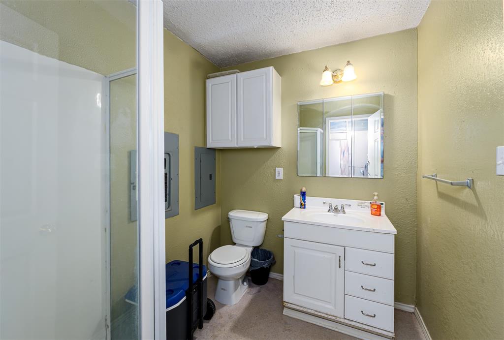 601 Houston School Road Red Oak, TX 75154 - Photo 15 of 32 Shower enclosure with a clear glass door, white vanity cabinet with a basin sink, wall-mounted mirrored medicine cabinet, and overhead wall sconce lighting
