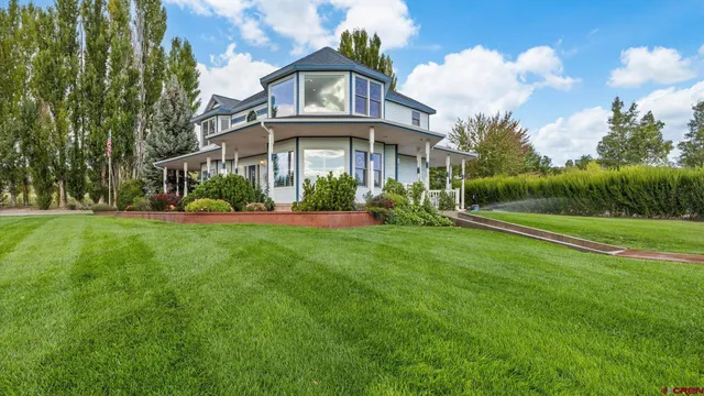 a view of a white house with a big yard and large trees