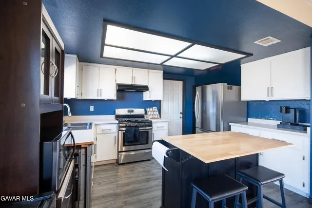 a kitchen with stainless steel appliances a stove a refrigerator a sink a stove and white cabinets