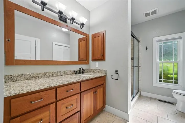 a bathroom with a granite countertop sink a toilet and mirror