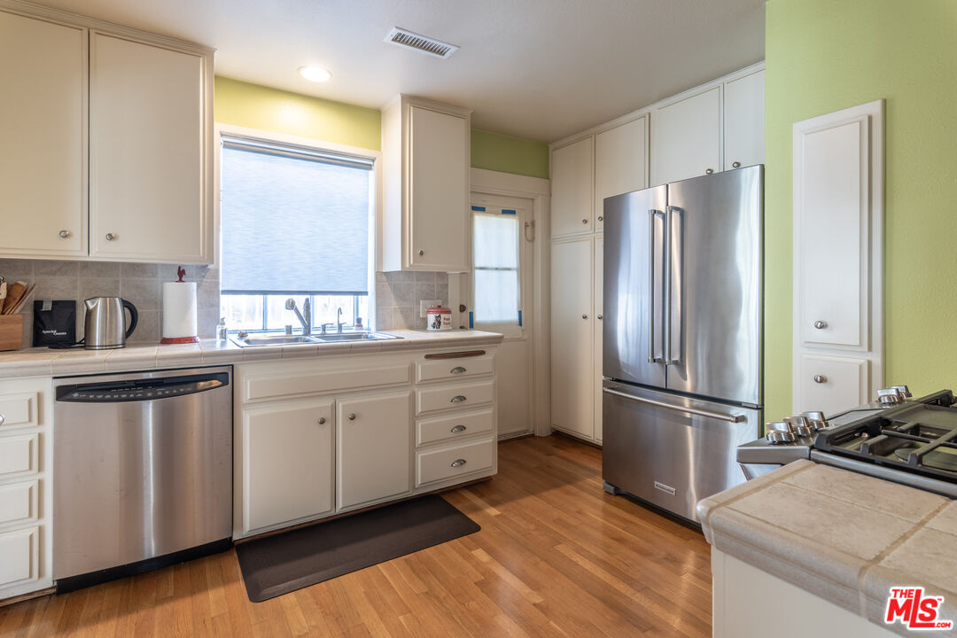 880 Wellesley Avenue Los Angeles, CA 90049 - Photo 13 of 29 a kitchen with stainless steel appliances a refrigerator sink and cabinets