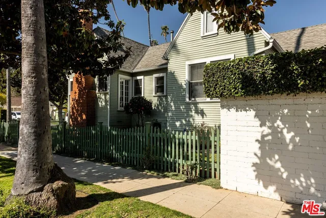 a view of a house with a small yard plants and large tree