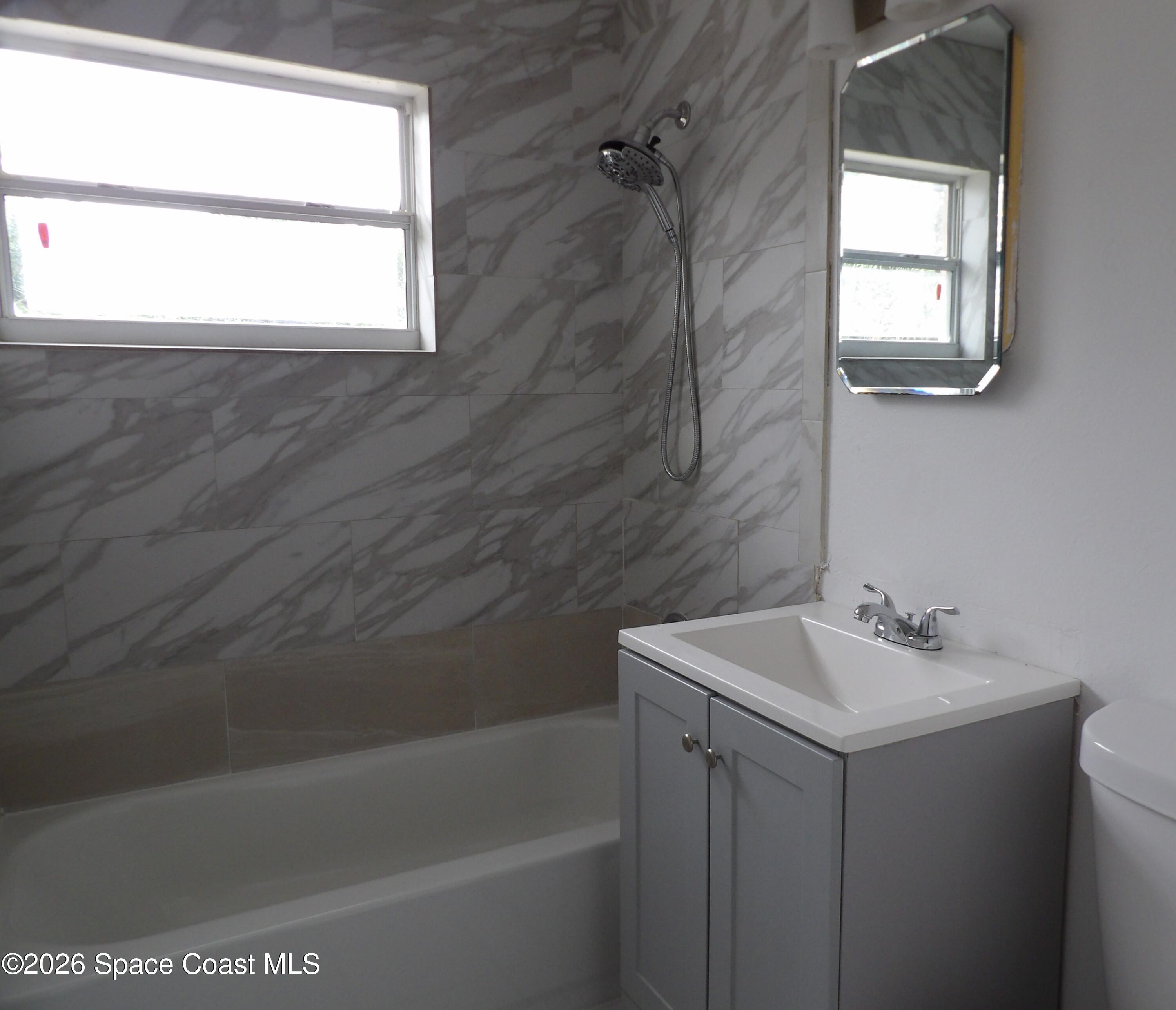 2107 Little John Road Melbourne, FL 32935 - Photo 11 of 13 a bathroom with a sink a bathtub and next to a window