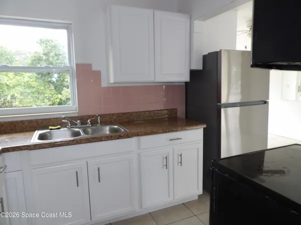 a kitchen with appliances a sink a counter and a window
