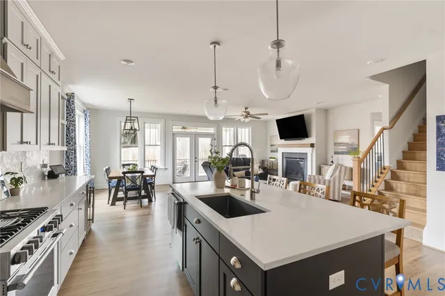 a kitchen with a stove a kitchen island a sink dishwasher a dining table and chairs with wooden floor