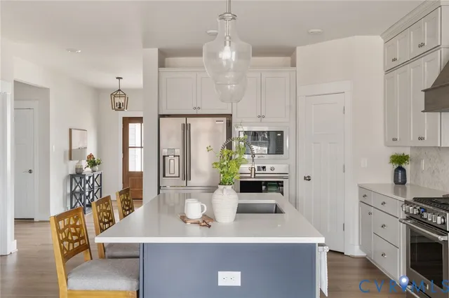 a kitchen with stainless steel appliances kitchen island granite countertop a stove a sink a refrigerator and a white cabinets