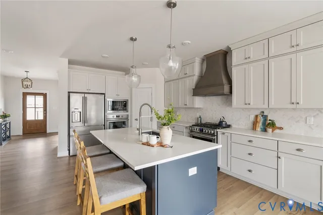 a kitchen with stainless steel appliances kitchen island granite countertop a table chairs refrigerator and microwave