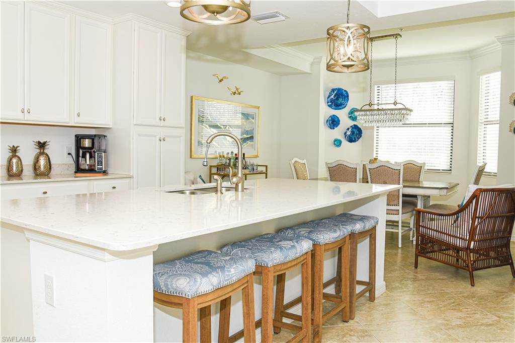 a dining table with a kitchen island white cabinets and chandelier