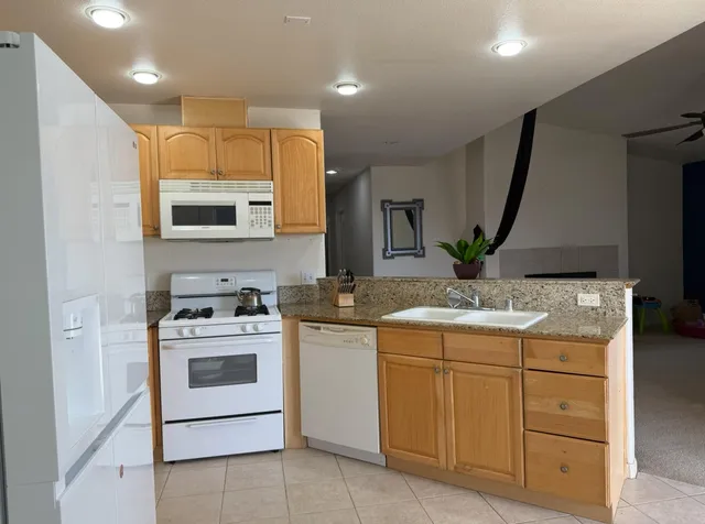 a view of kitchen with stainless steel appliances granite countertop a sink a stove and a refrigerator