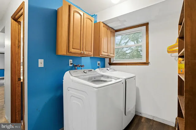 a view of an empty room with wooden floor and a kitchen