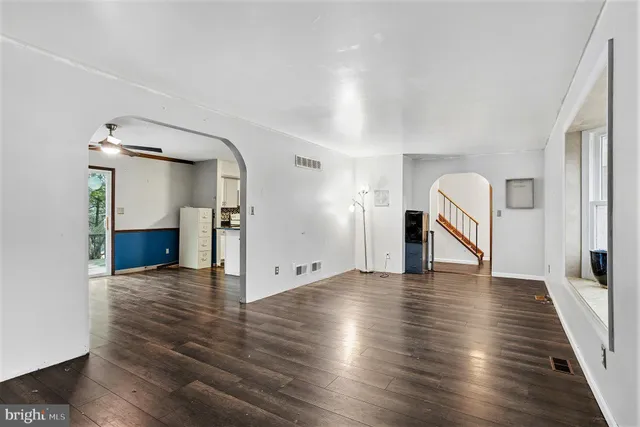 a kitchen with granite countertop a refrigerator a sink dishwasher and white cabinets with wooden floor