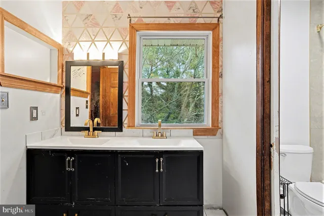 a bathroom with a double vanity sink window and a large mirror