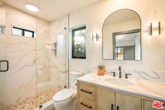 a bathroom with a granite countertop sink a toilet and a mirror