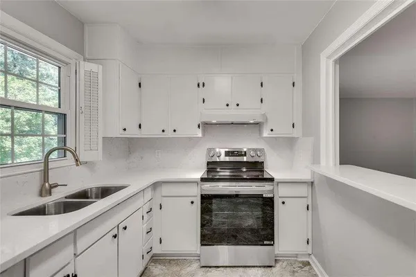 a kitchen with granite countertop a sink a stove and cabinets