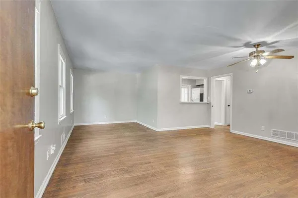 an empty room with wooden floor chandelier fan and windows