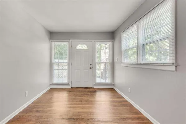 a view of an empty room with window and wooden floor