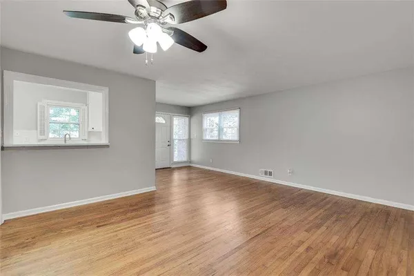 a view of an empty room with window and wooden floor