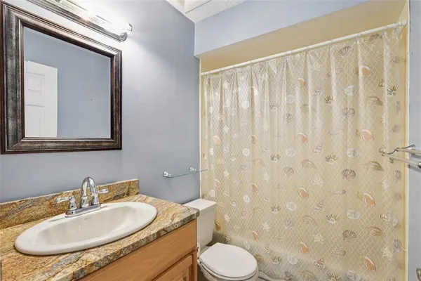 a bathroom with a granite countertop sink toilet and mirror