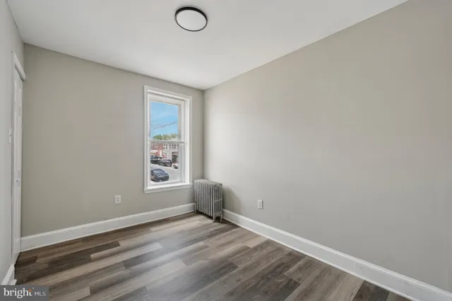 a view of empty room with window and wooden floor