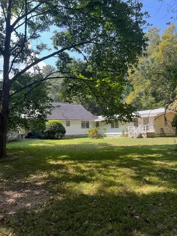 a view of a yard with plants and large trees