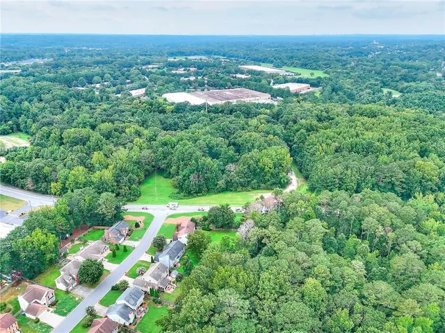 an aerial view of residential houses with outdoor space and trees