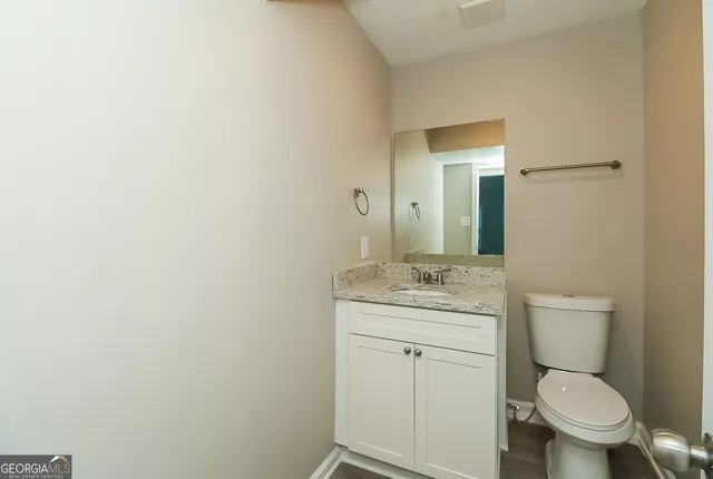a bathroom with a granite countertop toilet a mirror and a sink