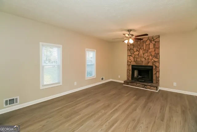 an empty room with chandelier fan and windows