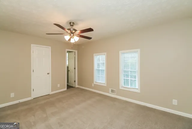 a view of an empty room with a ceiling fan and a window