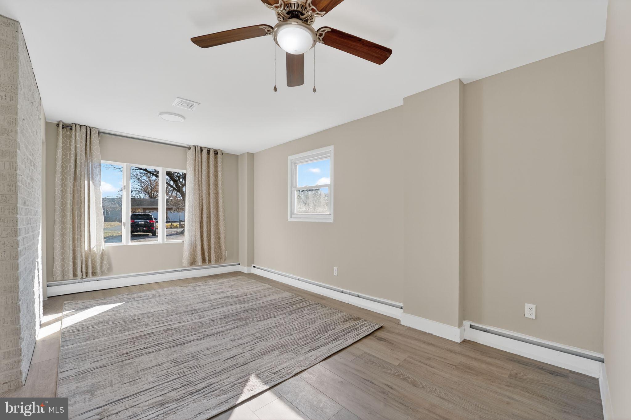 9337 Millbrook Road Ellicott City, MD 21042 - Photo 15 of 33 an empty room with wooden floor chandelier fan and windows