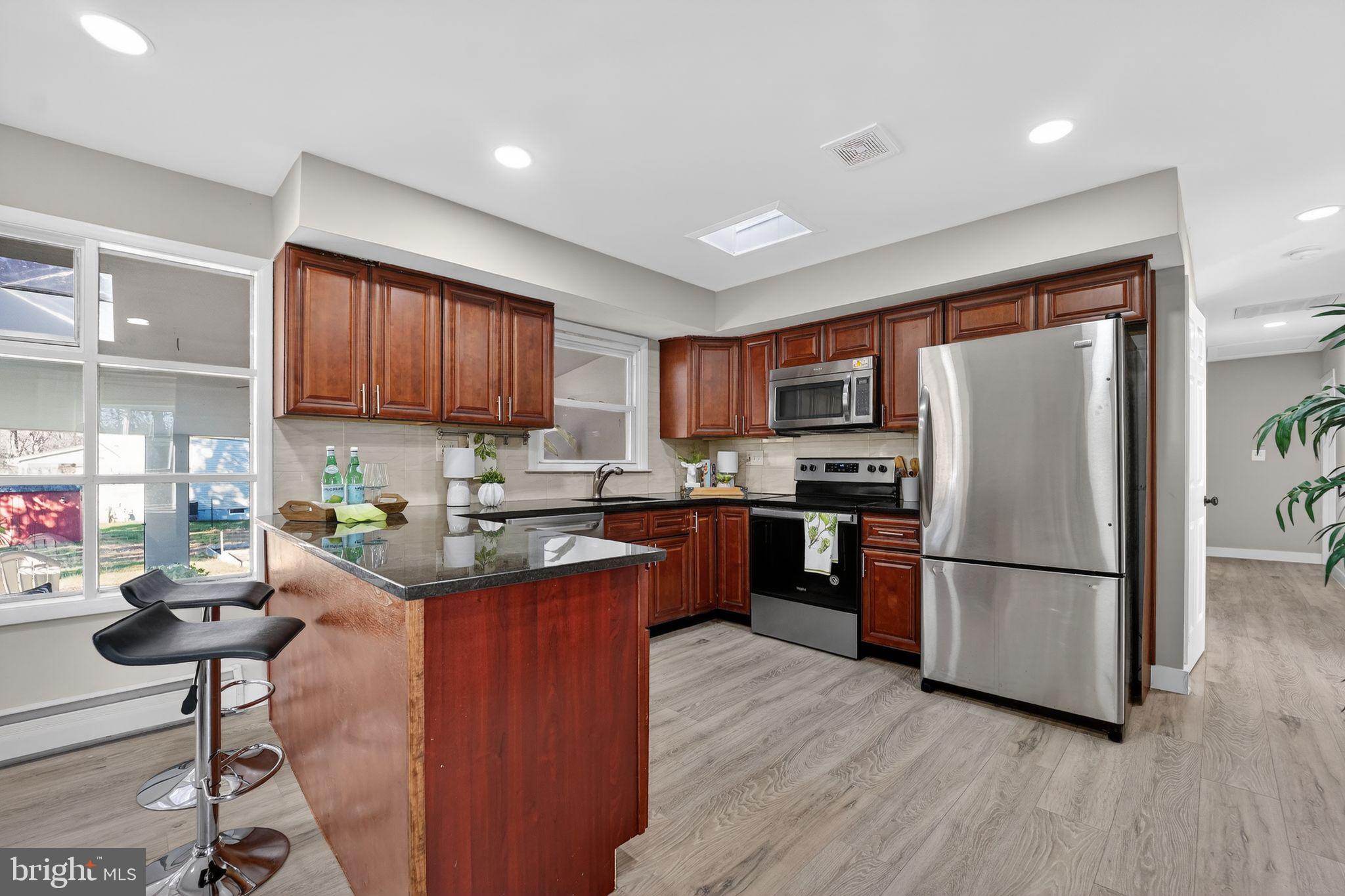 9337 Millbrook Road Ellicott City, MD 21042 - Photo 4 of 33 a kitchen with stainless steel appliances granite countertop a refrigerator stove top oven a sink and dishwasher with wooden floor