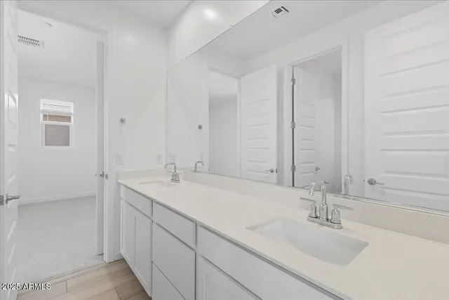 a bathroom with double sink and a mirror