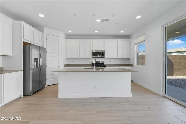 a large white kitchen with kitchen island a refrigerator a sink and a stove