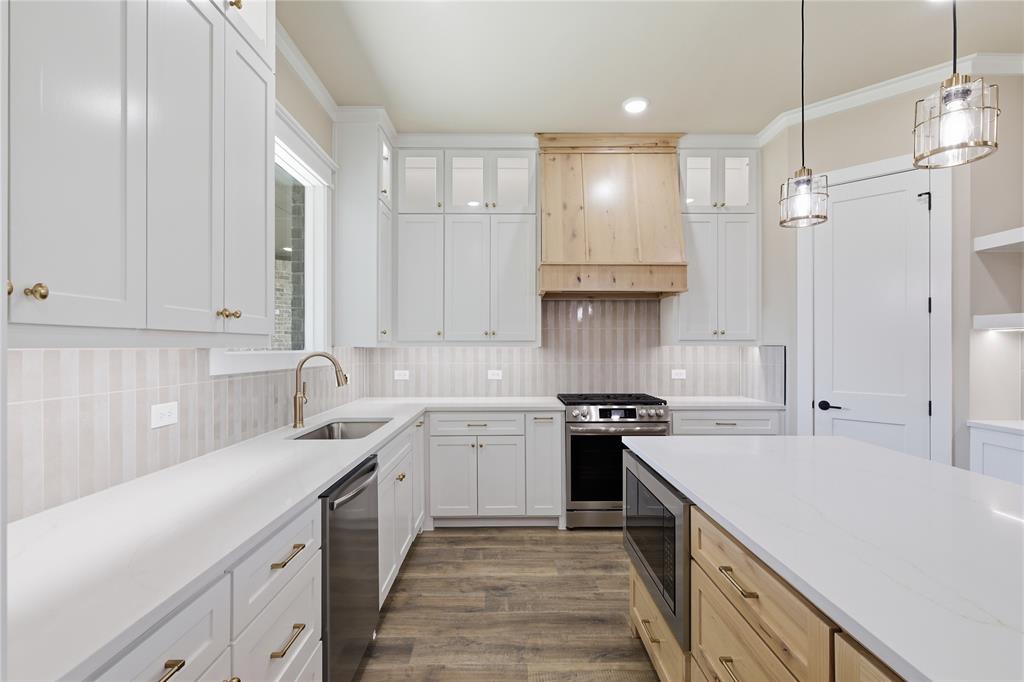 709 Anne Road Van Alstyne, TX 75495 - Photo 9 of 28 Modern kitchen featuring white cabinetry, light wood-finish flooring, a stainless steel range, and a kitchen island with built-in microwave
