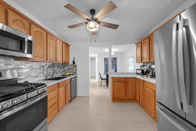 a large kitchen with stainless steel appliances granite countertop a stove top oven a sink a dishwasher with a dining table and chairs