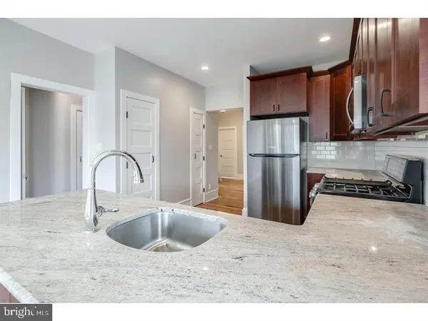 a kitchen with stainless steel appliances granite countertop a refrigerator a sink a stove with wooden cabinets