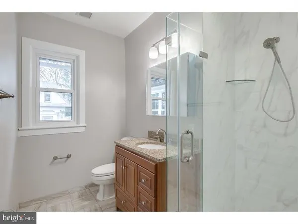 a bathroom with a granite countertop sink toilet a mirror and shower