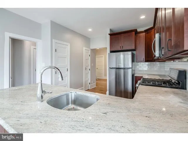 a kitchen with stainless steel appliances granite countertop a refrigerator a sink a stove with wooden cabinets