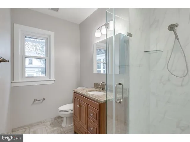 a bathroom with a granite countertop sink toilet a mirror and shower
