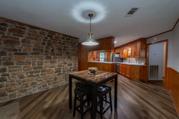 a kitchen with stainless steel appliances granite countertop a stove a refrigerator a dining table and chairs with wooden floor