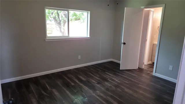 a view of an empty room with wooden floor fireplace and a window